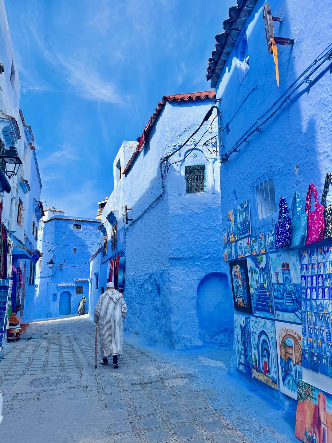 Elder in djellaba walking through the blue streets of Chefchaouen