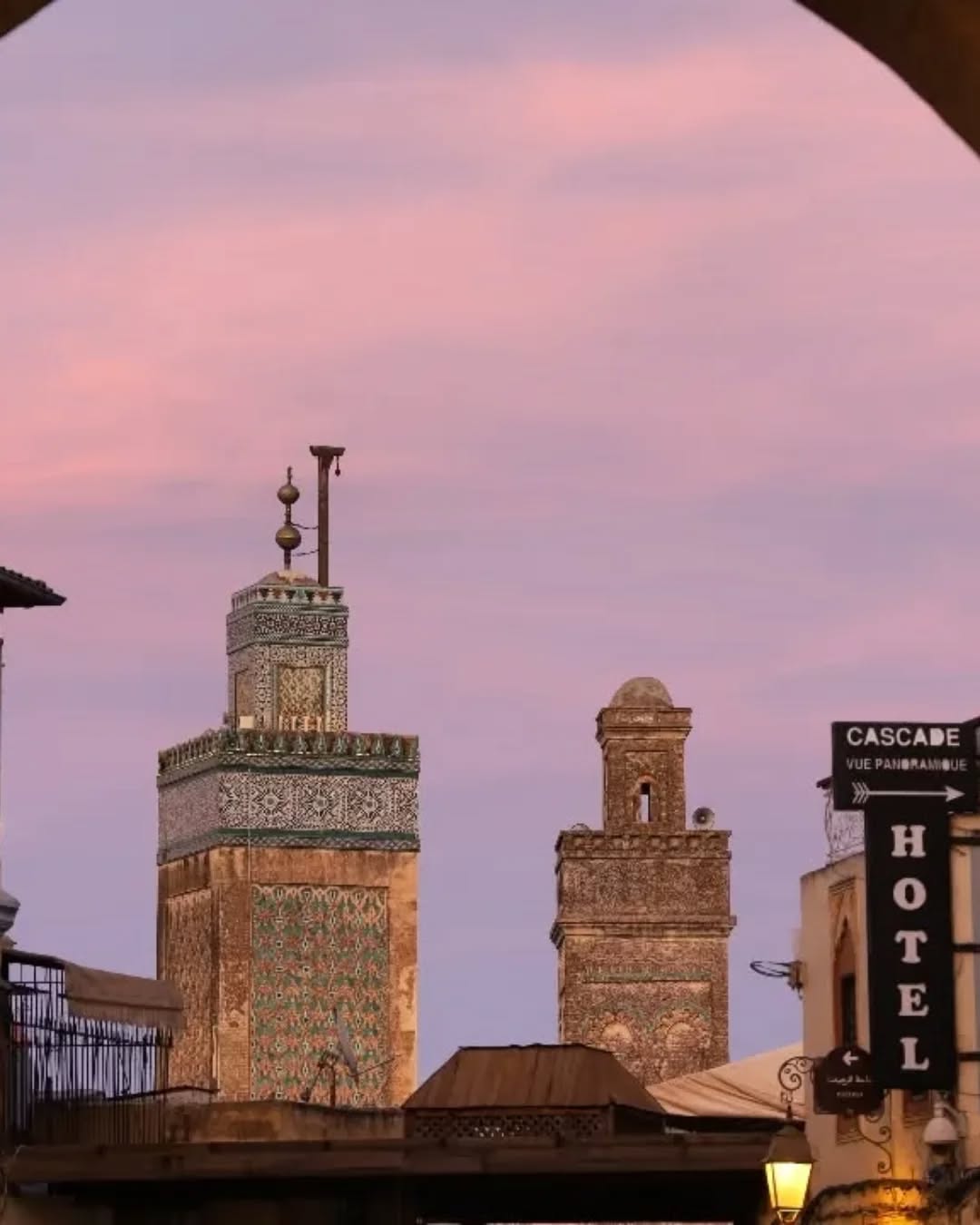 Bou Inania Minaret Bou Inania madrasa minaret at pink sunset framed by a medina arch