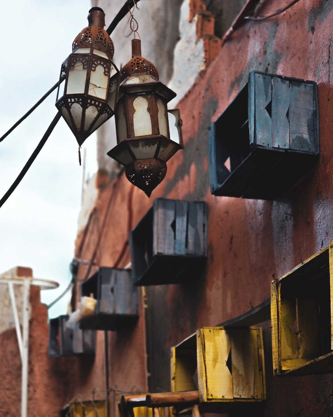Lantern Alley Moroccan lanterns hanging against a rose-red wall in Marrakech